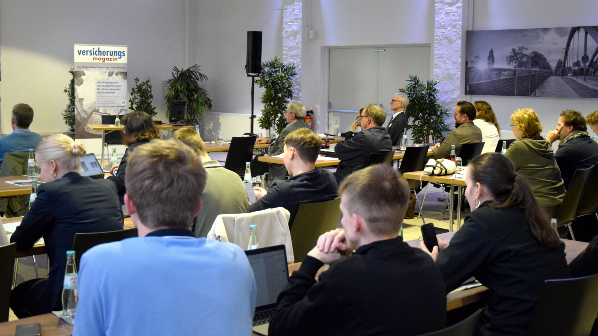 Plenumsteilnehmer sitzen im Konferenzraum und hören Vortrag zu