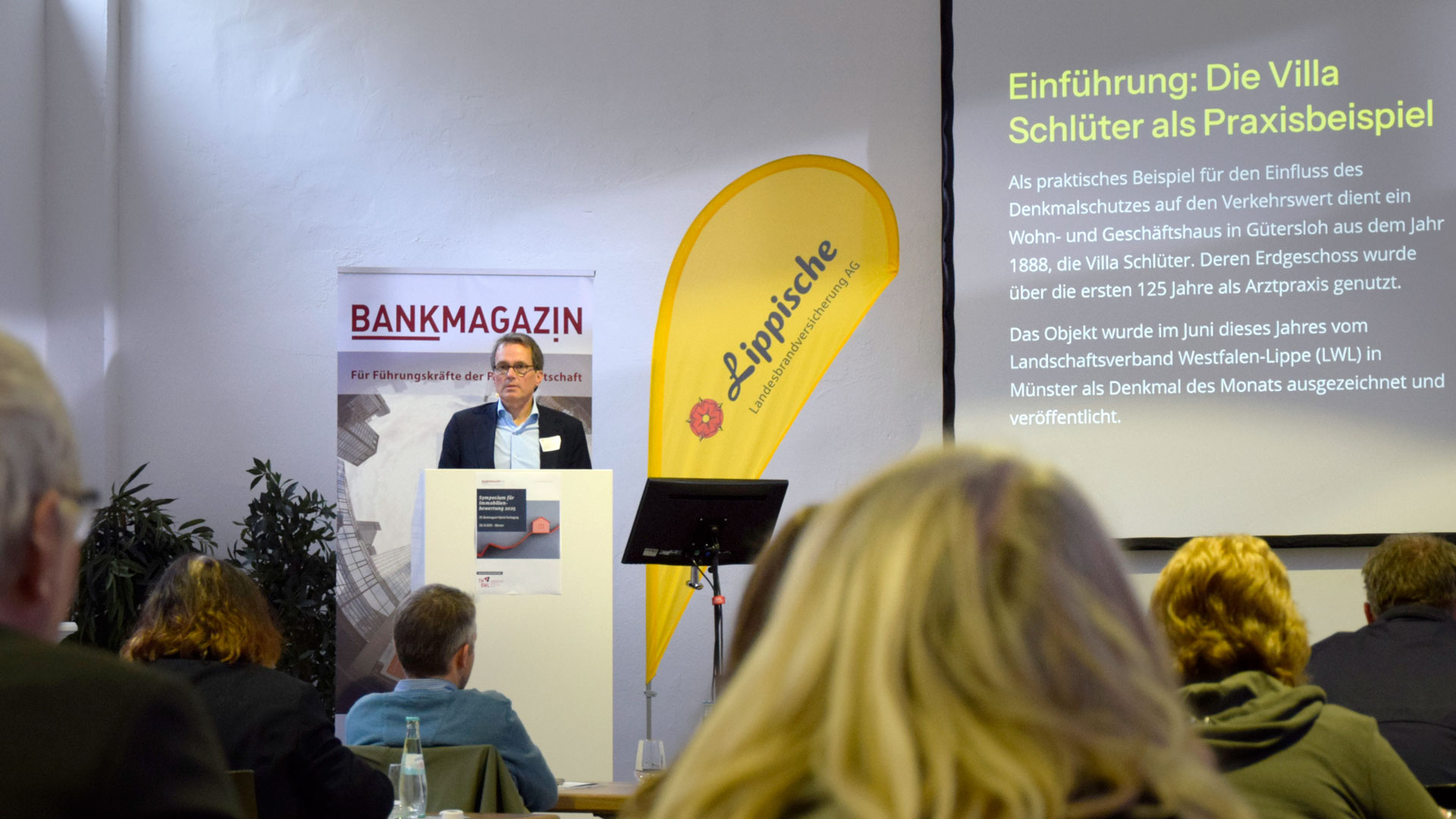 Referent auf der Bühne - im Vordergrund das Publikum