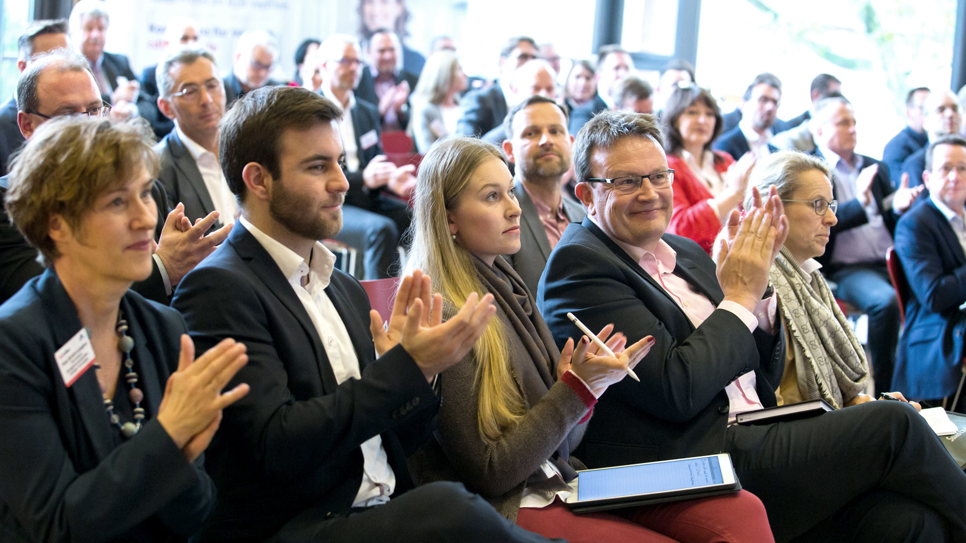 Klatschende Konferenzteilnehmer sitzend im Plenum 