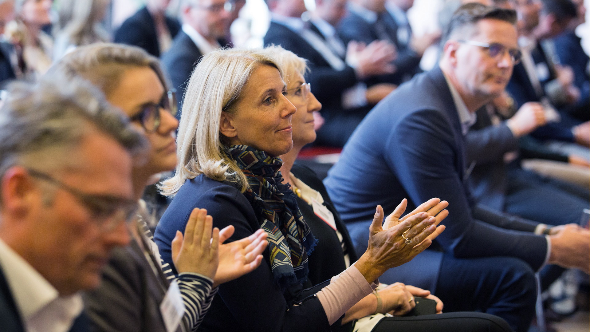 Klatschende Konferenzteilnehmer sitzend im Plenum 